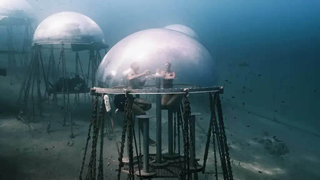 Man and woman enjoying an aperitif underwater at 1.5 Bar